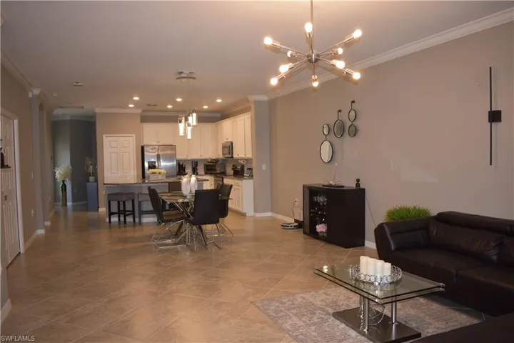 Living room featuring a chandelier, crown molding, and light tile patterned flooring
