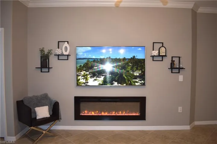 Living area featuring crown molding and a glass covered fireplace