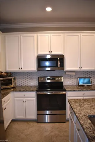 Kitchen with stainless steel appliances, white cabinetry, dark stone counters, and recessed lighting
