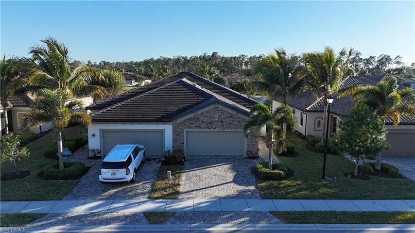 View of front of home featuring driveway, a tile roof, a front yard, and a garage