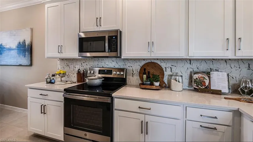 *Kitchen with light stone counters, stainless steel appliances, white cabinets. The actual unit has white tile backsplash.