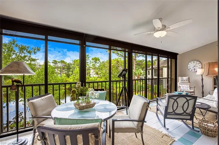 Sunroom featuring outdoor dining space, a ceiling fan, a wall of windows, and tile patterned flooring
