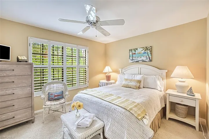 Carpeted bedroom with ceiling fan and baseboards