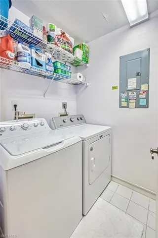Laundry area featuring separate washer and dryer, electric panel, and light tile patterned floors