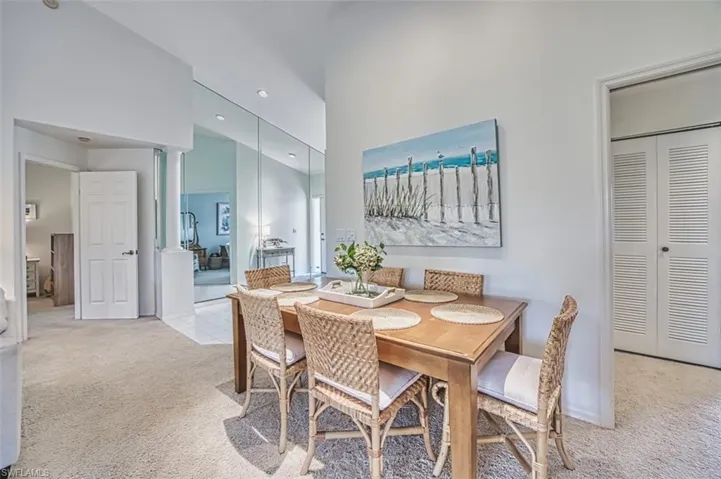 Dining room with light carpet, lofted ceiling, and recessed lighting