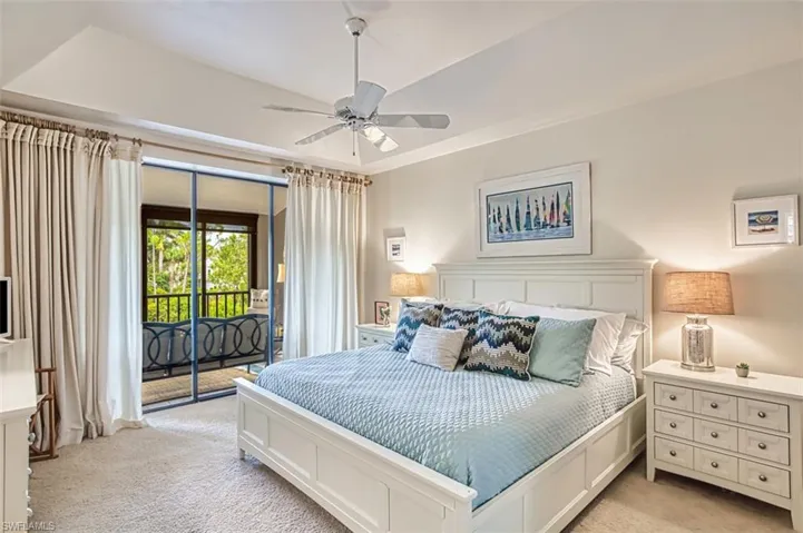 Bedroom with light colored carpet, access to outside, a tray ceiling, and ceiling fan