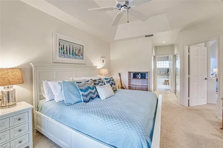 Bedroom featuring light carpet, a tray ceiling, and a ceiling fan