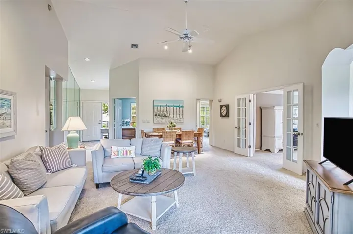 Living room featuring light colored carpet, ceiling fan, french doors, and high vaulted ceiling