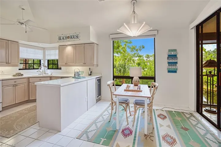 Kitchen with light tile patterned floors, light countertops, a peninsula, a ceiling fan, and wine cooler