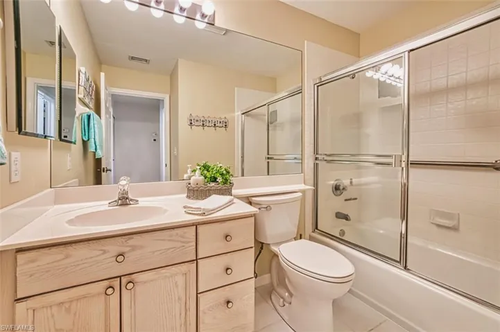 Full bathroom with vanity, tile patterned flooring, and bath / shower combo with glass door