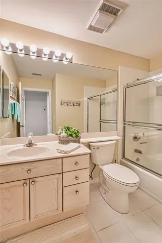 Full bath featuring tile patterned floors, vanity, and shower / bath combination with glass door