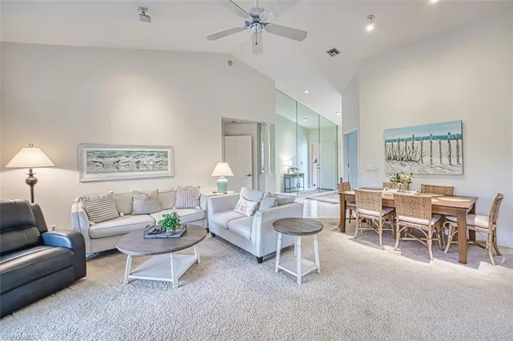 Living room with light carpet, high vaulted ceiling, and a ceiling fan