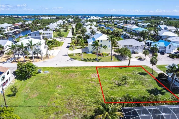 Aerial perspective of suburban area with property boundaries highlighted and a nearby body of water