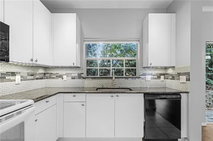 Contemporary kitchen featuring white cabinetry, dark countertops, and a mosaic tile backsplash