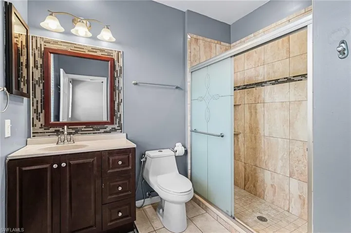 Bathroom featuring a single vanity with a solid surface countertop, an undermount sink, and a framed mirror