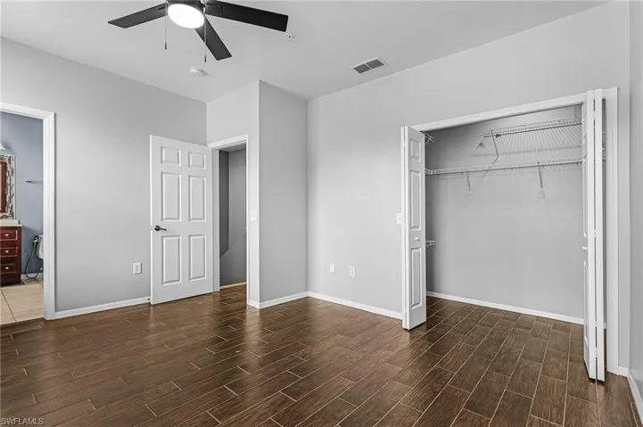 Spacious room featuring wood-finish flooring, a ceiling fan, and a bi-fold door closet with wire shelving