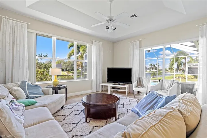 Tiled living room featuring ceiling fan and a tray ceiling