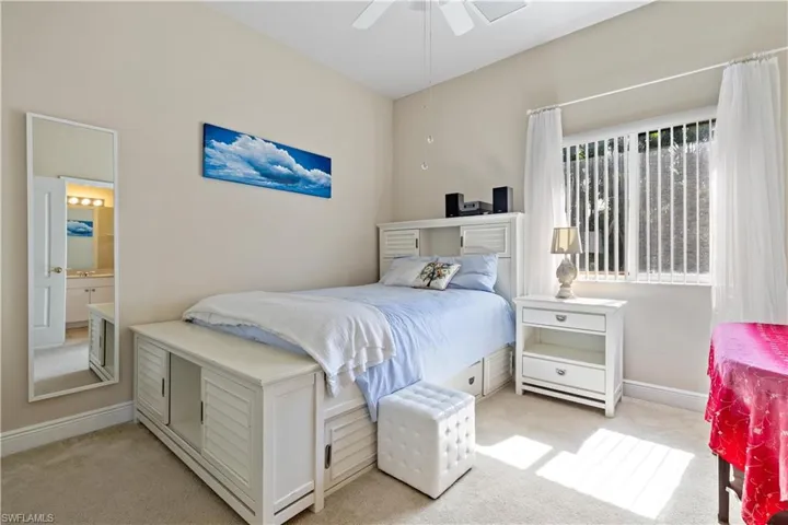 Bedroom with light carpet, ensuite bathroom, and ceiling fan
