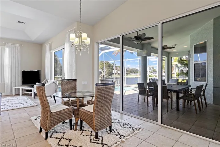 Tiled dining space featuring ceiling fan with notable chandelier