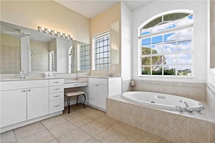 Bathroom featuring vanity, ceiling fan, and jacuzzi tub