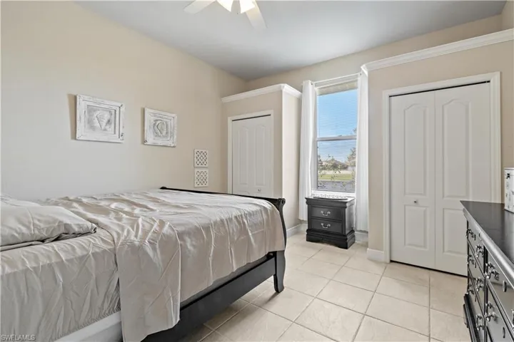 Tiled bedroom featuring two closets and ceiling fan