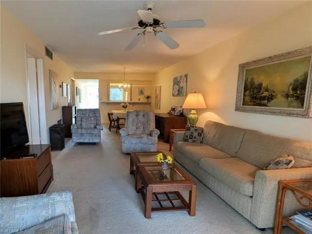 Carpeted living room featuring ceiling fan and a chandelier