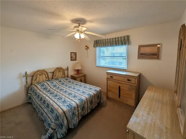 Carpeted bedroom featuring a textured ceiling and ceiling fan