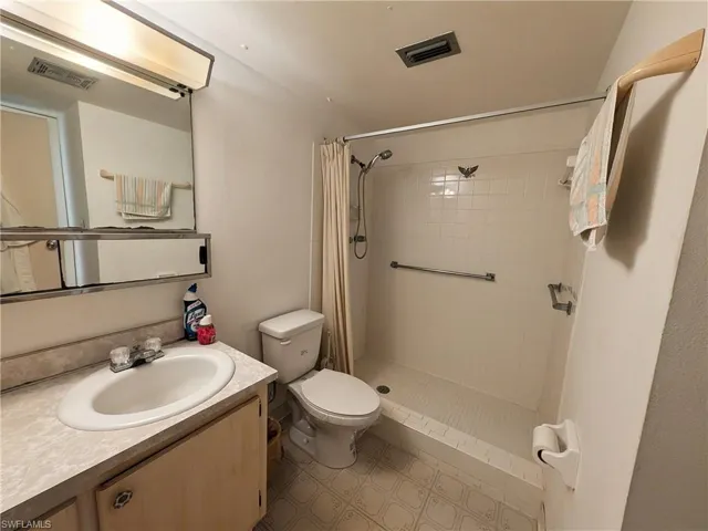 Full bathroom featuring a shower stall, vanity, and light flooring