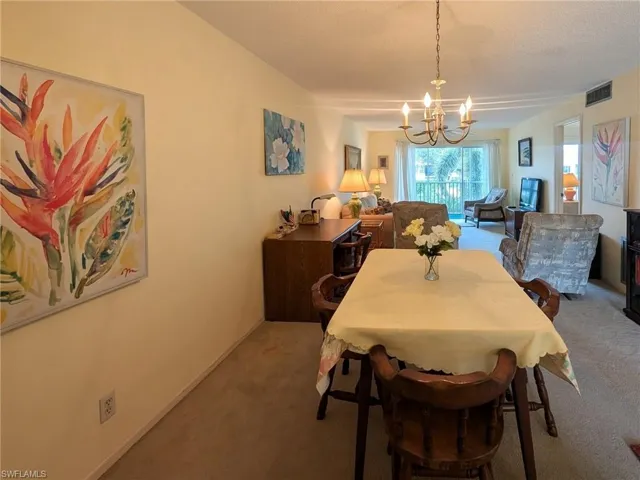 Carpeted dining room with a chandelier and a textured ceiling