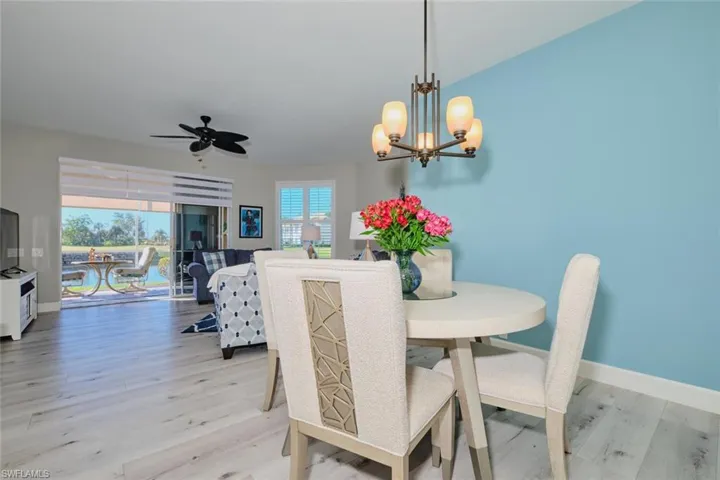 Dining space with ceiling fan with notable chandelier and light hardwood / wood-style floors