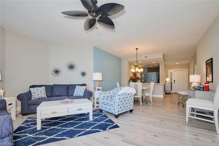 Living room with ceiling fan with notable chandelier and light hardwood / wood-style flooring