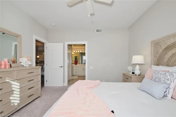 Carpeted bedroom with ceiling fan and ensuite bathroom