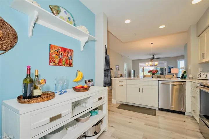 Kitchen featuring white cabinets, light wood-type flooring, decorative light fixtures, and appliances with stainless steel finishes
