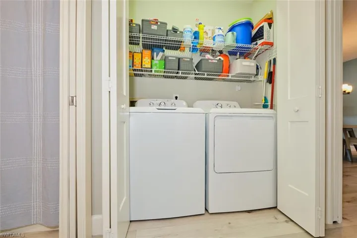 Washroom with washing machine and clothes dryer and light hardwood / wood-style flooring