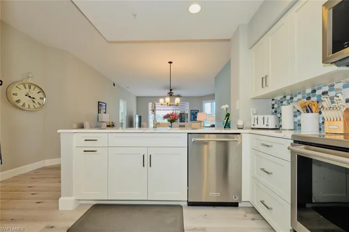 Kitchen with a chandelier, stainless steel appliances, kitchen peninsula, and light hardwood / wood-style floors