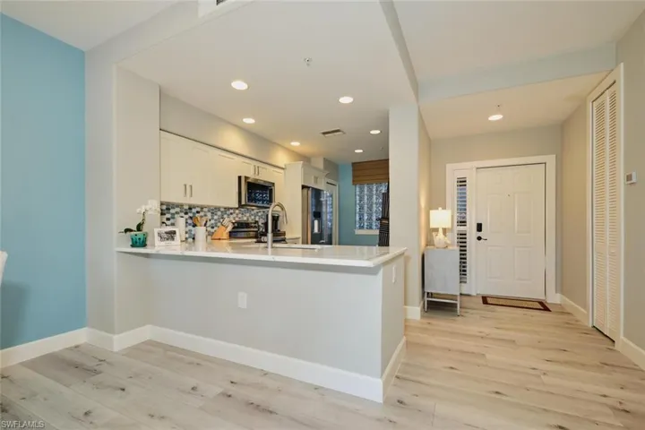 Kitchen with backsplash, white cabinets, light hardwood / wood-style flooring, appliances with stainless steel finishes, and kitchen peninsula