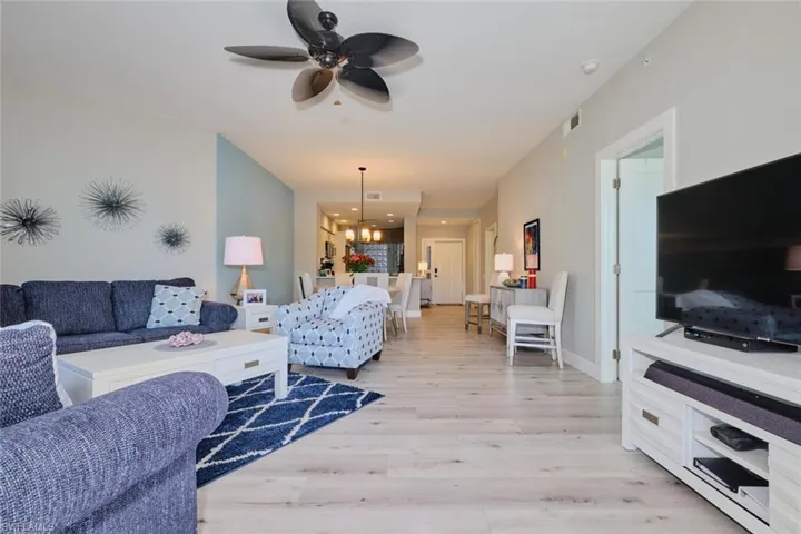 Living room featuring ceiling fan with notable chandelier and light hardwood / wood-style flooring