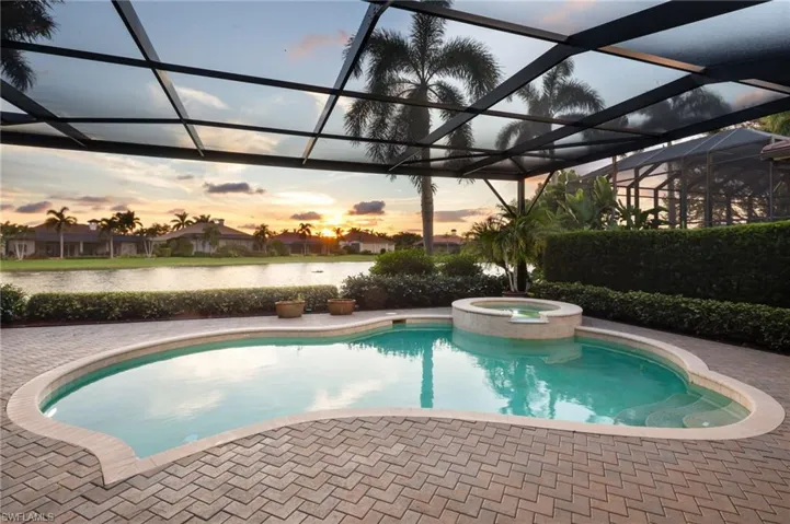 View of pool with a lanai, a sunroom, a pool with connected hot tub, and a water view
