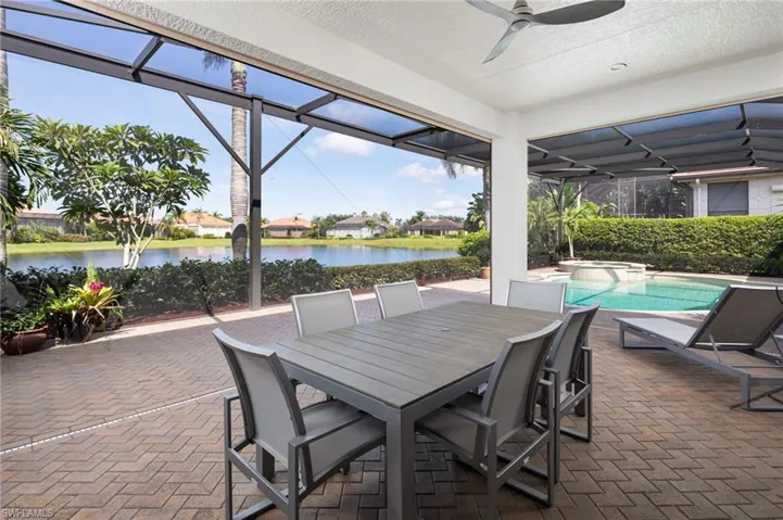 View of patio with a lanai, a pool with connected hot tub, outdoor dining space, and a ceiling fan