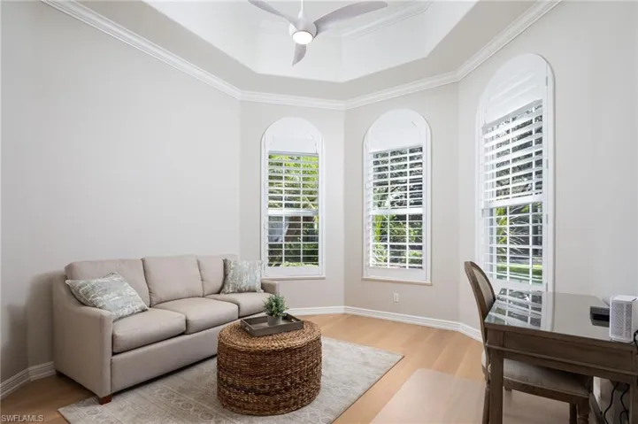 Office area with ornamental molding, a tray ceiling, light wood-type flooring, and ceiling fan