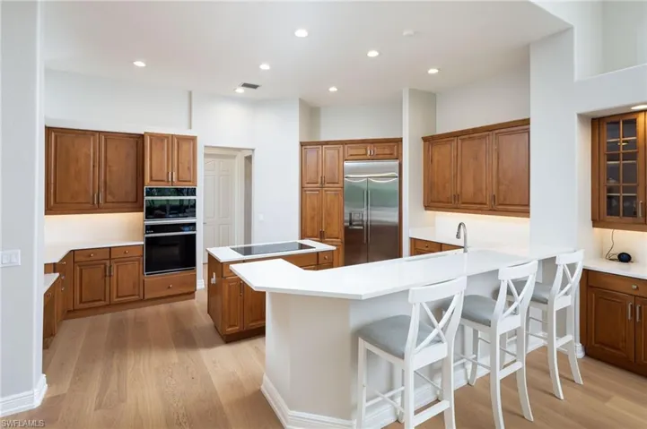 Kitchen with brown cabinets, a kitchen bar, a peninsula, a kitchen island, and light wood-style flooring