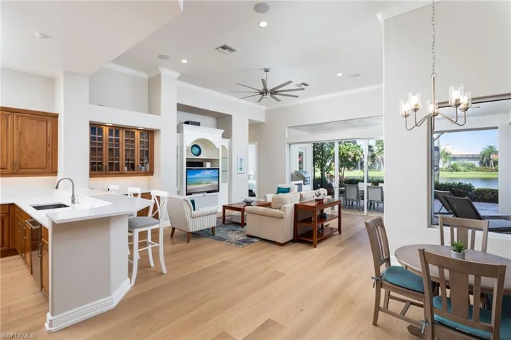 Living room with ornamental molding, a ceiling fan, light wood-style flooring, a chandelier, and recessed lighting