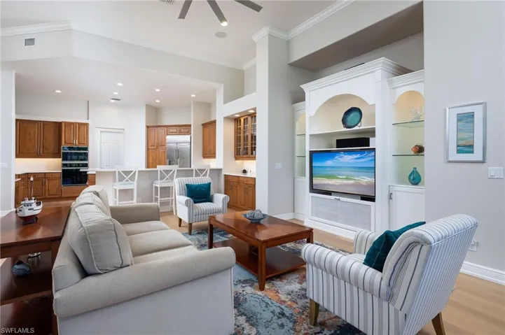 Living room with light wood finished floors, ornamental molding, recessed lighting, and a ceiling fan