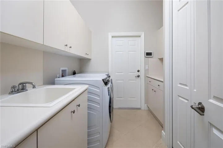 Laundry area featuring cabinet space, light tile patterned flooring, and washing machine and dryer