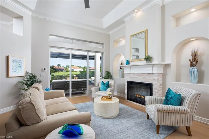 Living area featuring wood finished floors, ornamental molding, and a stone fireplace