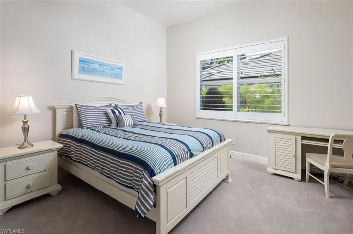 Carpeted bedroom featuring a desk and baseboards