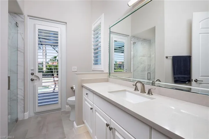 Bathroom featuring vanity, a marble finish shower, and light tile patterned floors