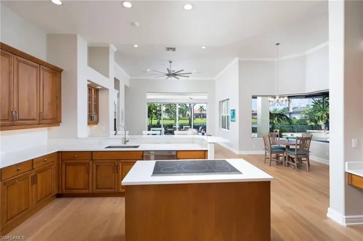 Kitchen with brown cabinetry, ornamental molding, light wood-type flooring, a peninsula, and recessed lighting