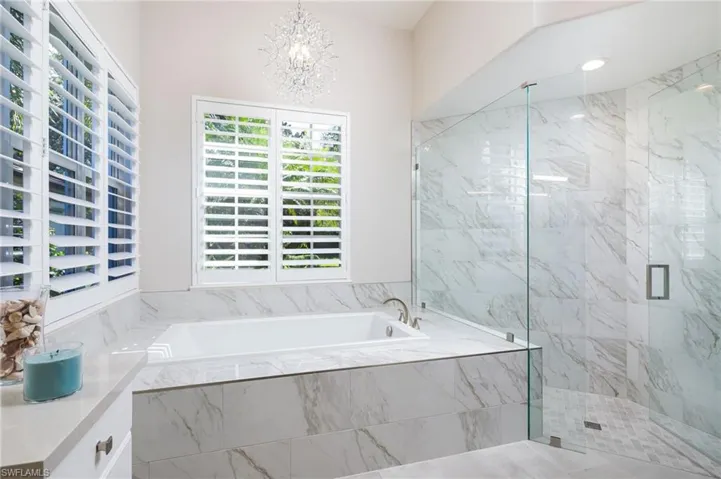 Full bathroom with a garden tub, a marble finish shower, a chandelier, and vanity