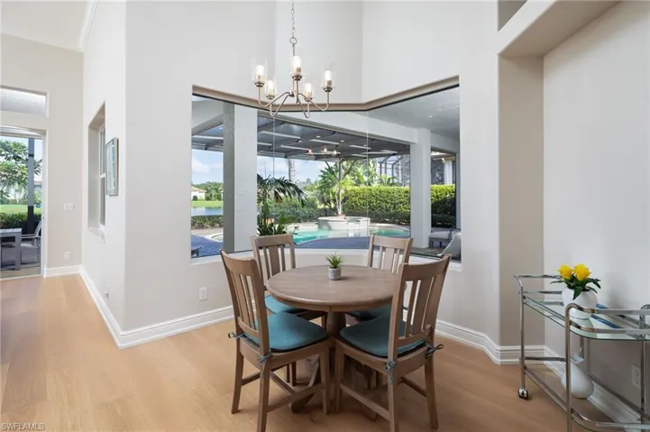 Dining room with wood finished floors, a chandelier, a water view, and ornamental molding